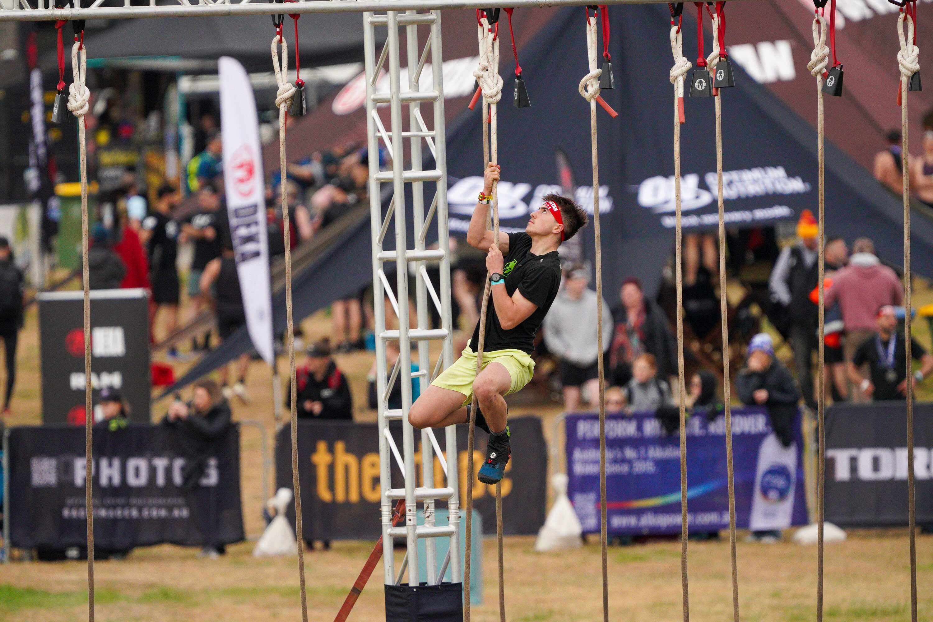 man climbing up rope with crowd watching at Spartan Melbourne