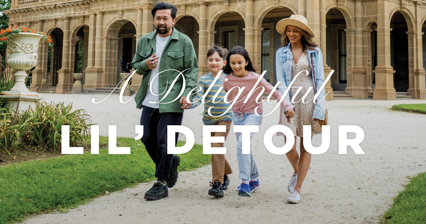 two adults and two children holding hands and walking in front of Werribee Park Mansion