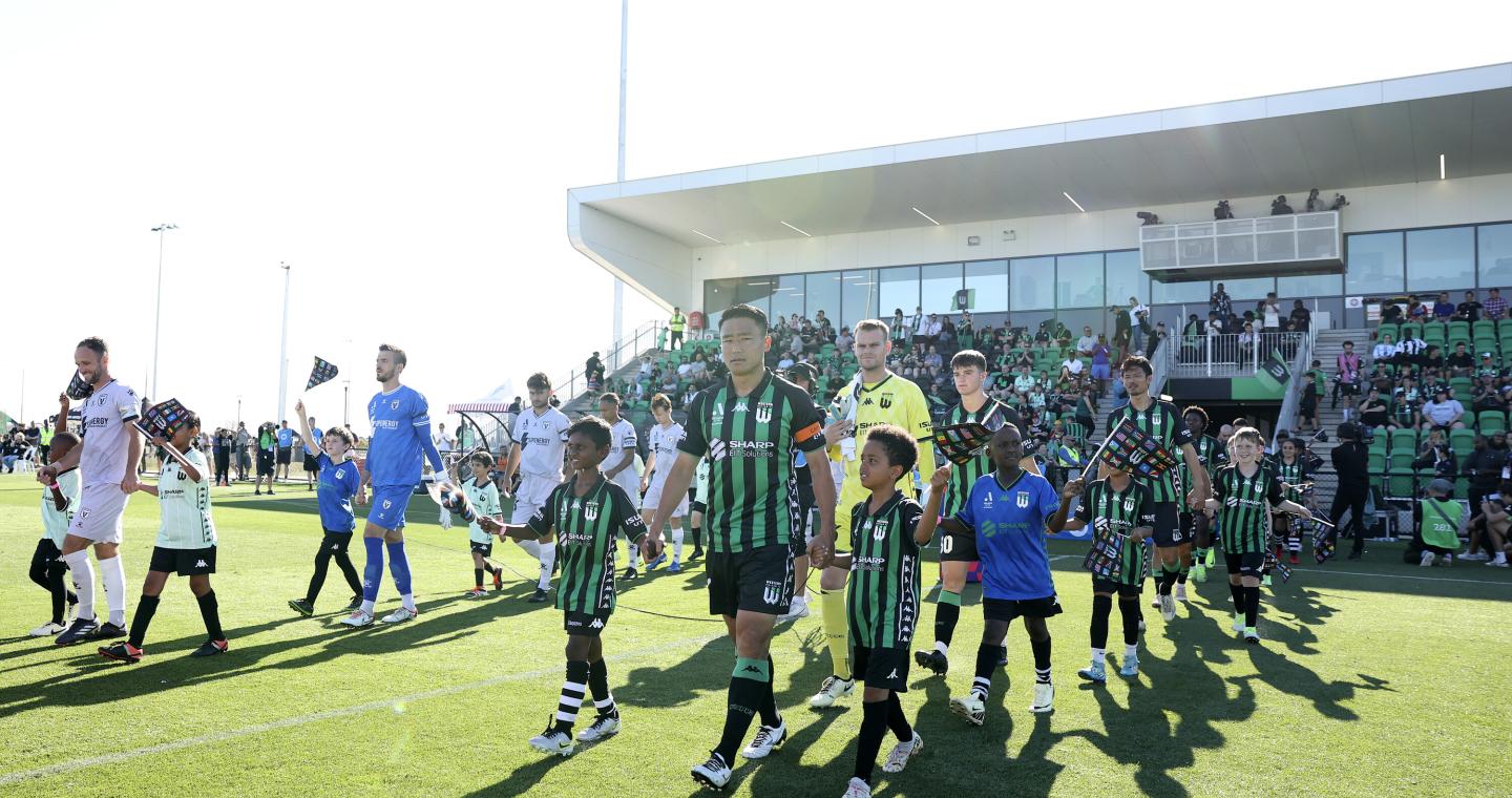 Western United players and children walking out onto the pitch at Ironbark Fields