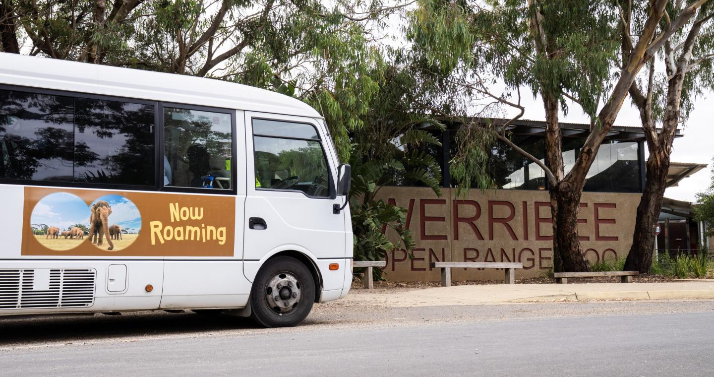 a shuttle bus parked in front of a sign for Werribee Open Range Zoo