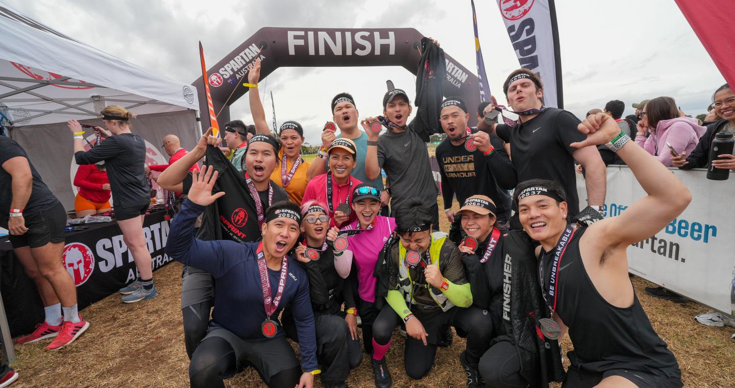 group of athletes wearing medals and smiling at finish line
