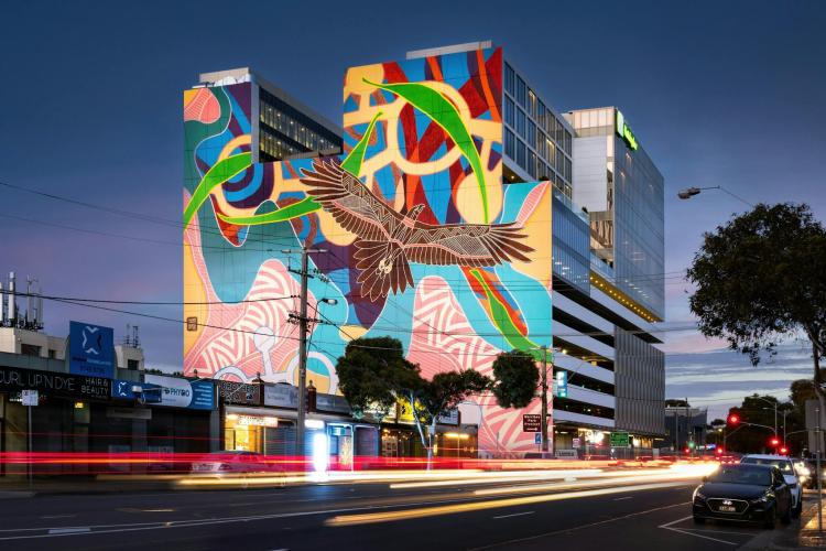 A large Indigenous mural featuring Bunjil on a building facade at night