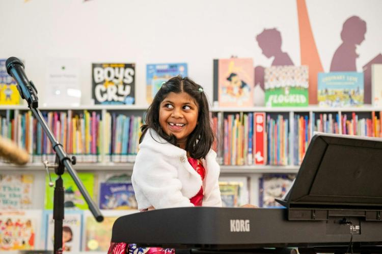 young girl sitting at music keyboard