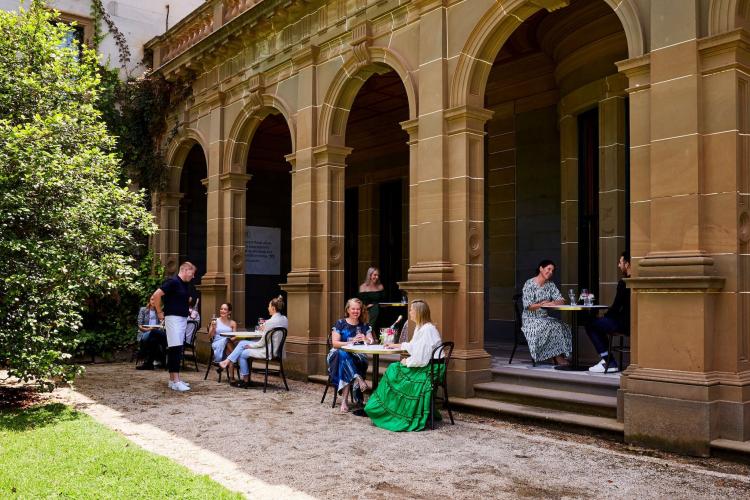 adults sitting outside in front of Werribee Park Mansion eaves