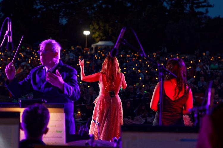 Performer at night singing in front of crowd with candles