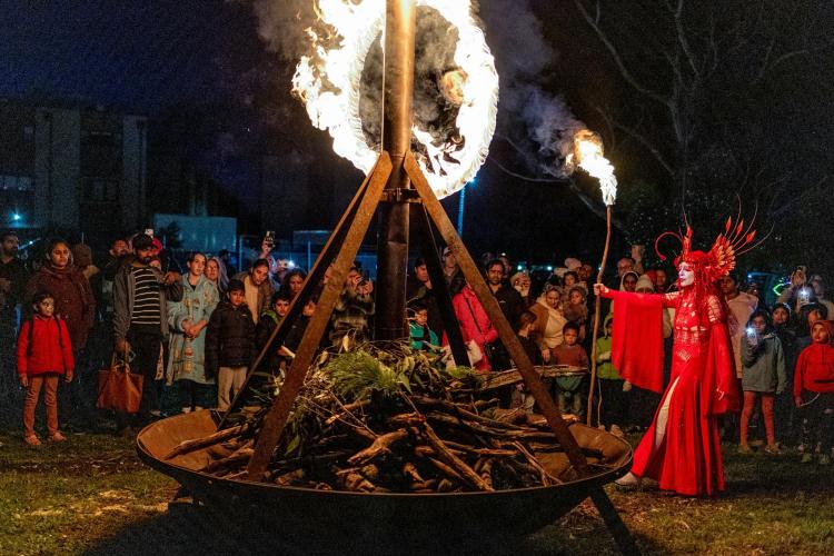 performer lighting giant bonfire with crowd watching at night