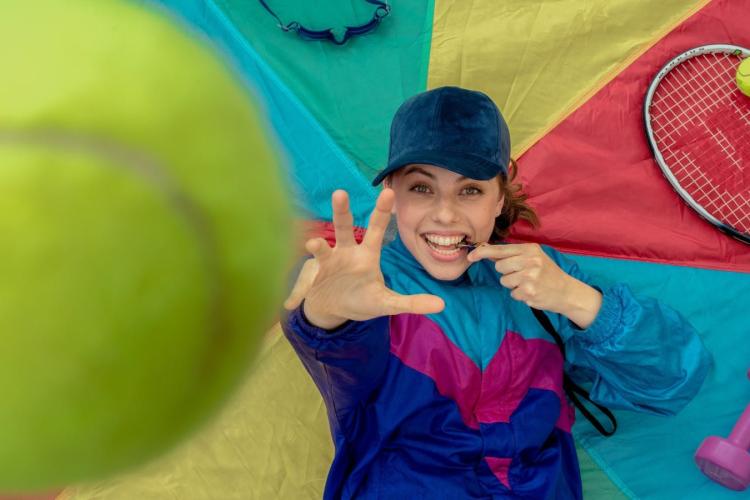 Smiling coach throwing a tennis ball