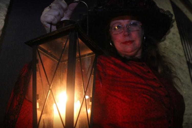 lady in old time dress holding up lamp