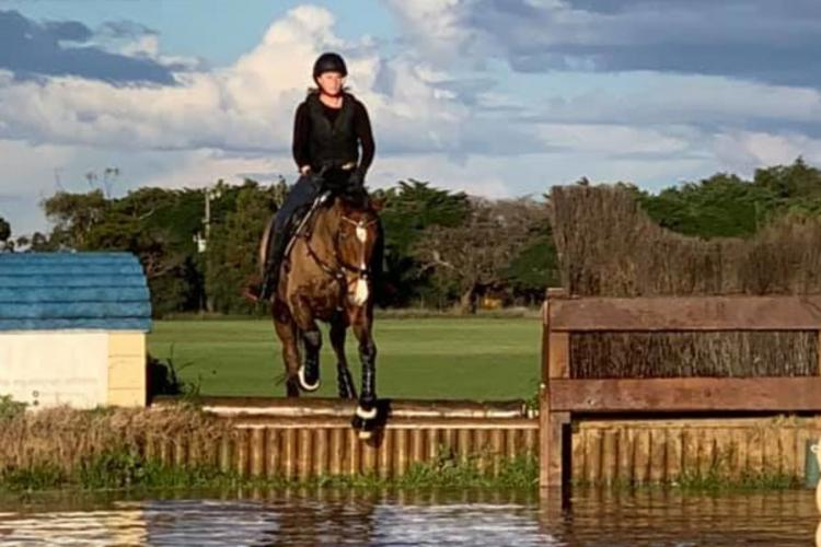 rider on a horse jumping over water obstacle course