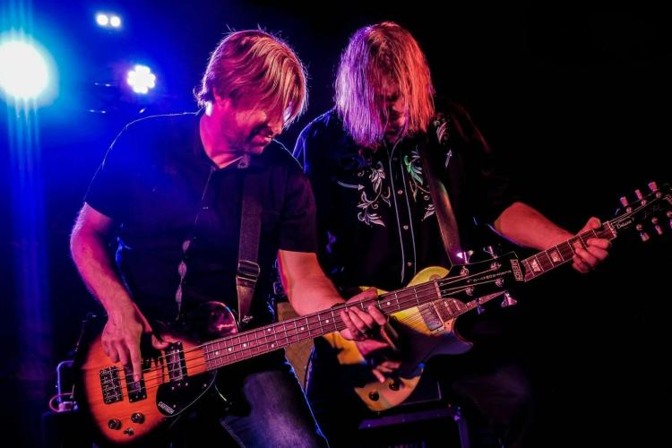 2 man performing, both playing guitar