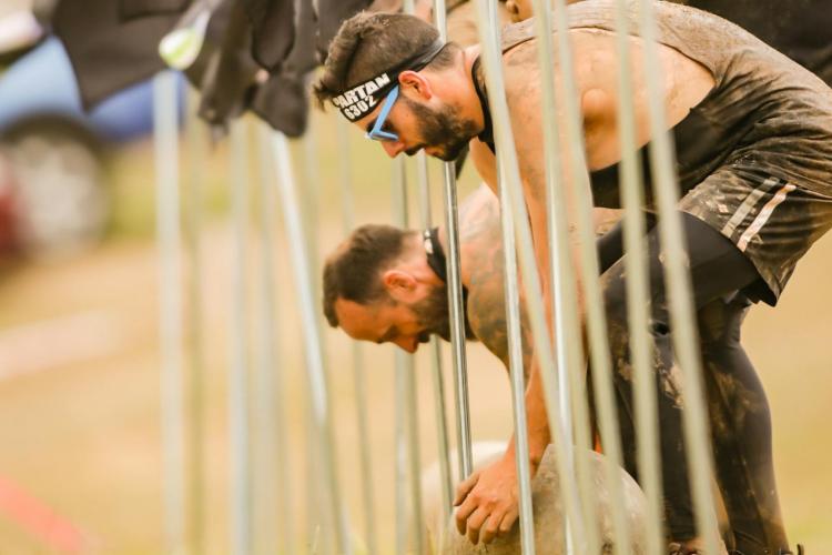 Male participants of a Spartan race preparing to carry weights as part of an obstacle