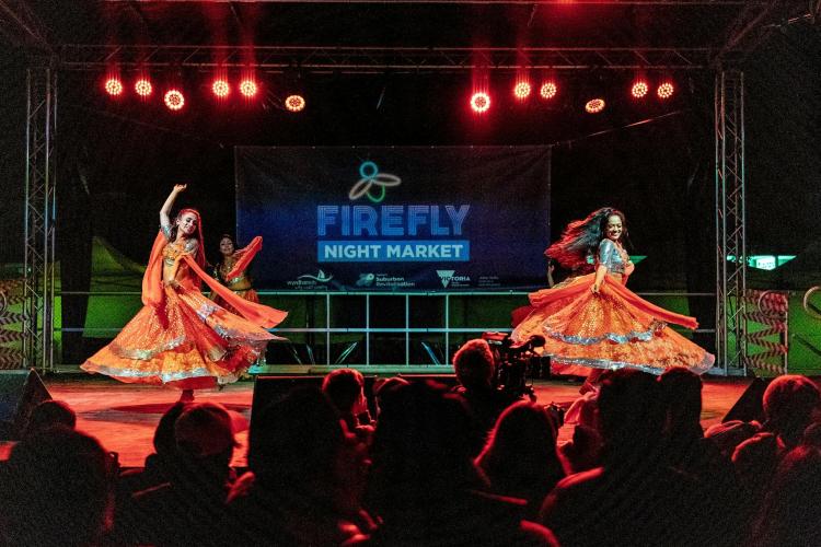 two performers dancing on stage at night with Firefly signage behind them