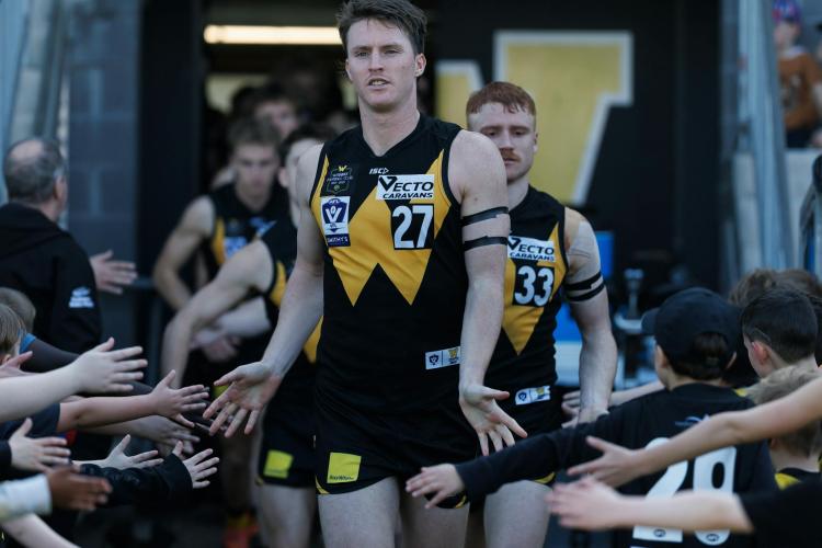 Werribee Football club players walking out onto the group hi-fiving spectators