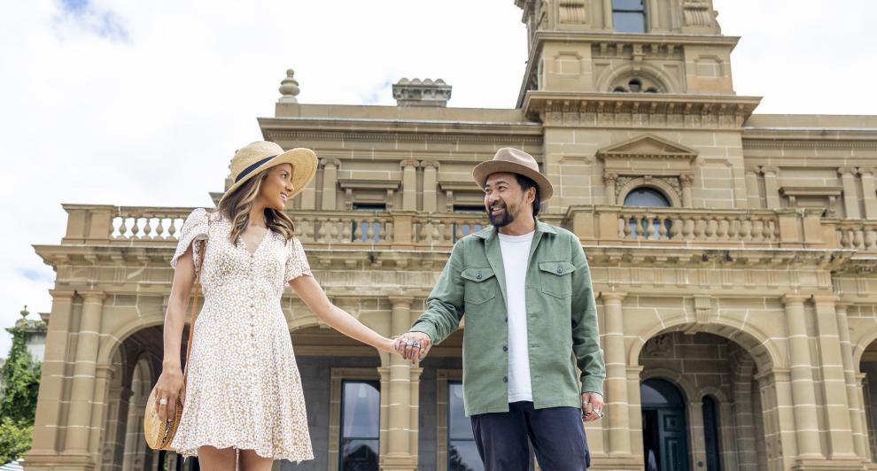 couple holding hands standing in front of Werribee Park Mansion