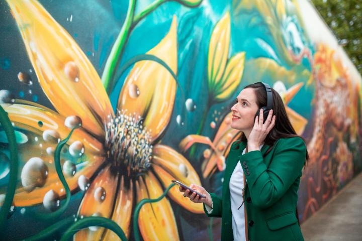 Lady viewing street art while listening to audio