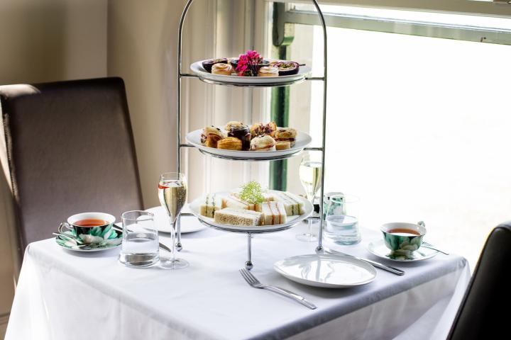 a tower of high tea pastries on a table with a white table cloth