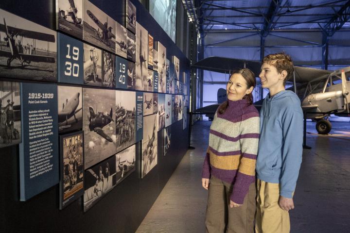 a woman and teenage son smiling and looking at a display of aviation history